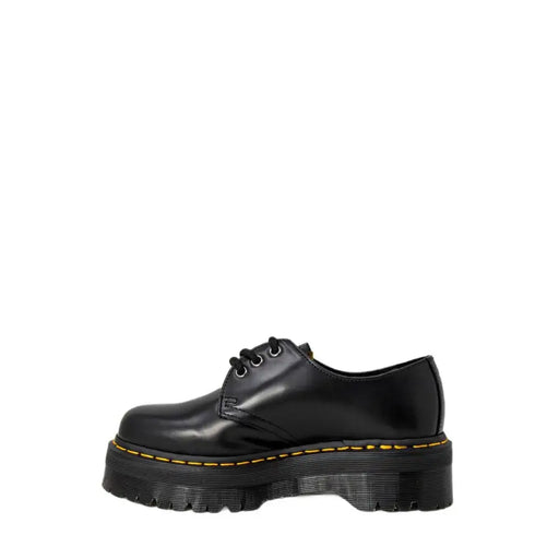 Chaussures Dr Martens pour femmes, en cuir noir à plateforme, lacets, surpiqûres jaunes et semelle épaisse.