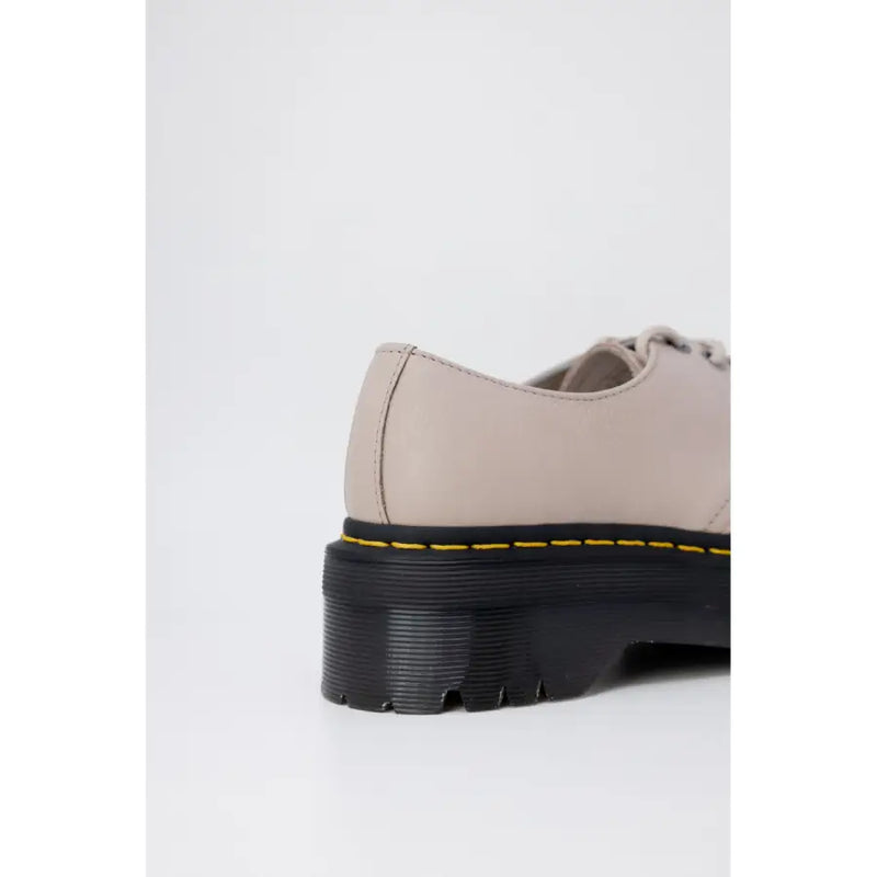 Beige leather dr martens womens slip-on shoes shown from the back side highlighting the material and design