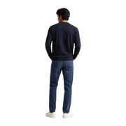 Un homme porte un sweat-shirt ea7 en coton noir, coupe classique, avec des manches longues bleu marine et un jean en denim foncé.