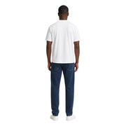 Un homme portant un t-shirt blanc en coton ea7 pour homme, coupe classique, avec un jean bleu foncé