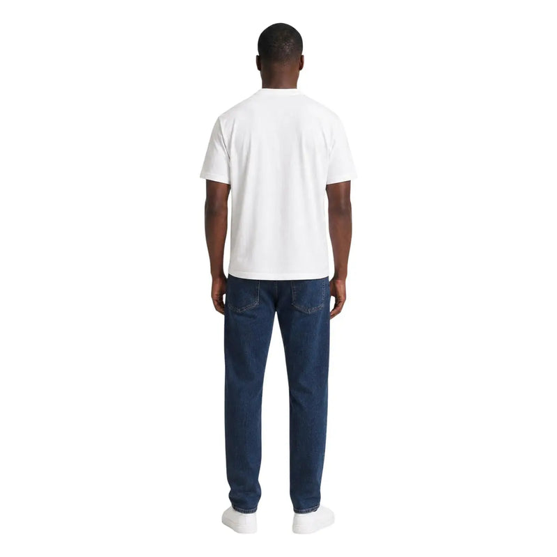 Un homme portant un t-shirt blanc en coton ea7 pour homme, coupe classique, avec un jean bleu foncé