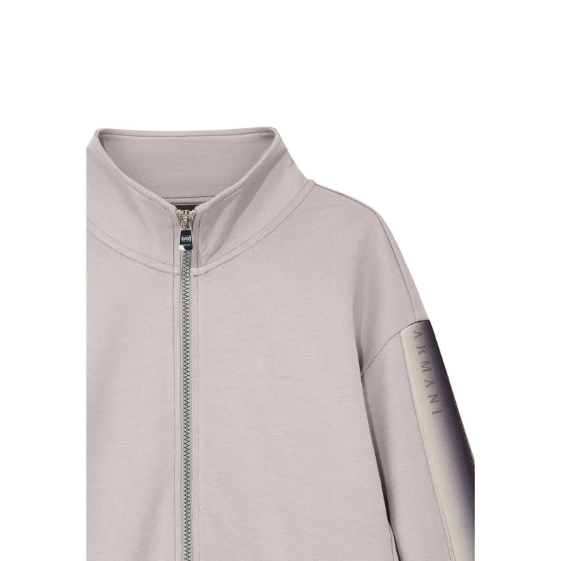 Une élégante veste zippée gris clair Armani avec empiècement dégradé aux manches et fermeture éclair métallique, assortie à une combinaison beige en coton mélangé EA7 pour femme