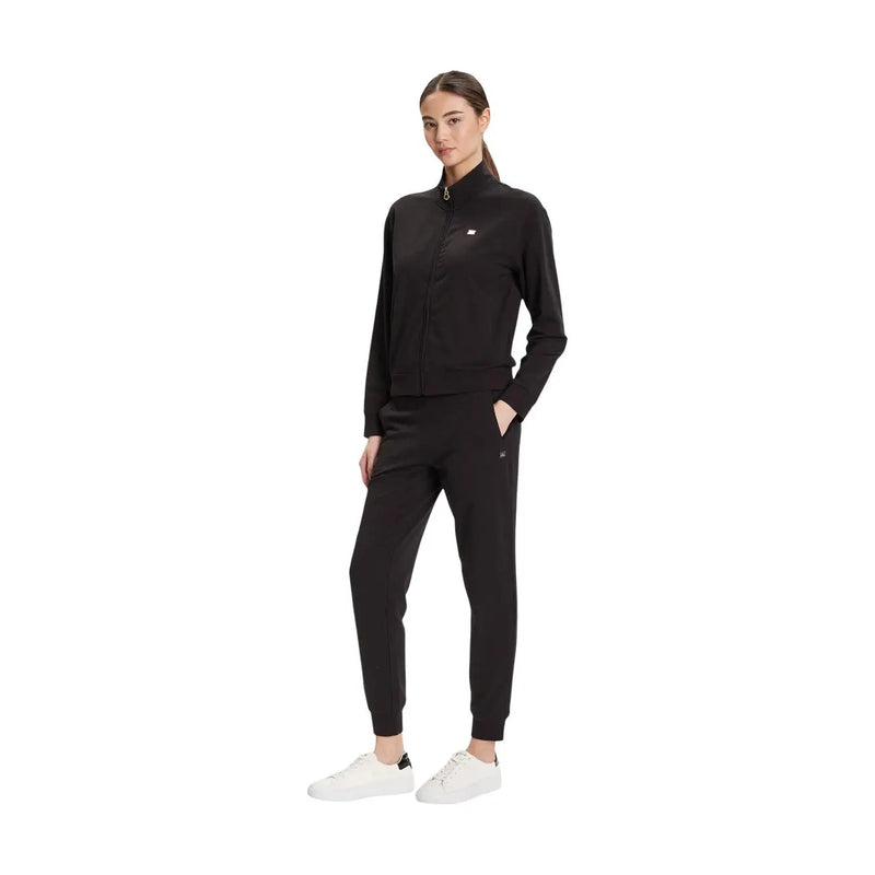 Ea7 Combinaison noire en coton à col roulé pour femme, portée avec un survêtement noir zippé Tommy Hilfiger et des baskets blanches.