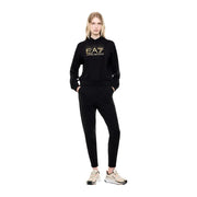 Ea7 Combinaison pantalon en coton noir à capuche pour femme, idéale pour l'automne, comprenant un sweat à capuche noir EA7 Emporio Armani avec logo brodé doré et un pantalon de jogging assorti.