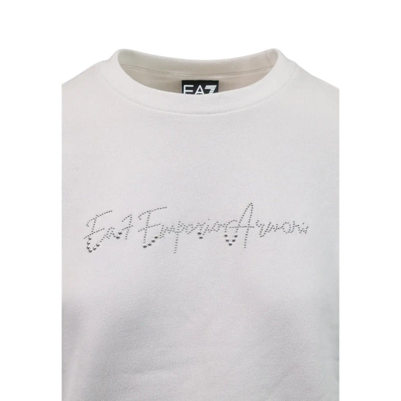 Sweat-shirt blanc EA7 Emporio Armani avec logo strass étincelant sur la poitrine, porté avec une combinaison en coton gris.