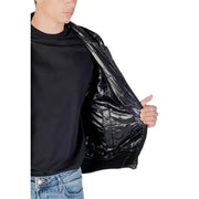 Person wearing an open black shiny puffer jacket with a black t-shirt and blue jeans