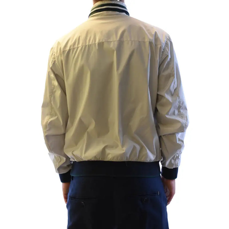 Blouson aviateur beige à col et poignets côtelés noirs en nylon léger, associé à un blazer à col roulé zippé gris en polyester de la marque Fay Men.