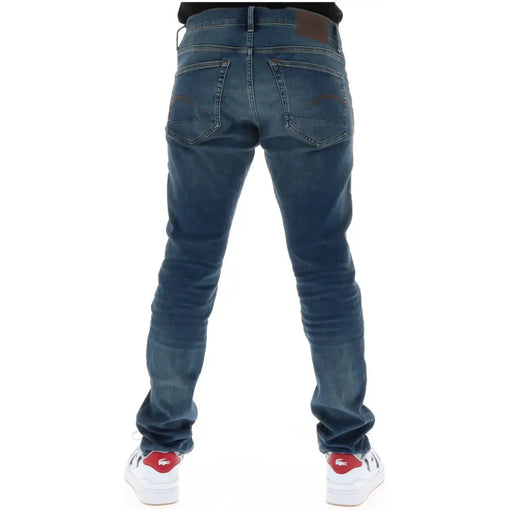 Jean G-Star bleu foncé pour homme, coupe slim, braguette boutonnée, coton stretch, vu de dos avec empiècements en cuir marron.