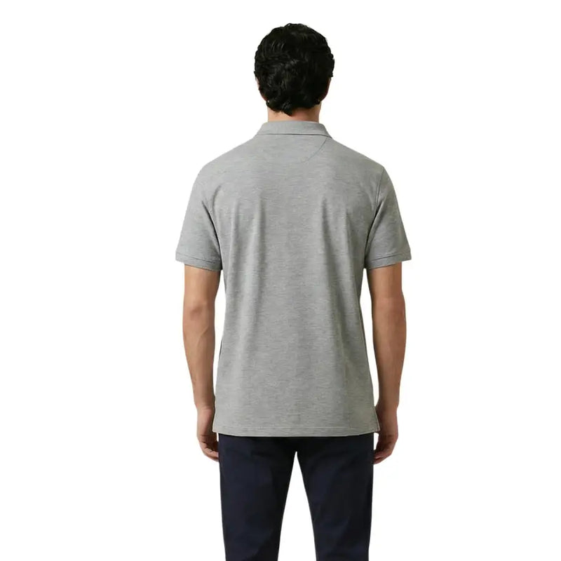 Un homme portant un polo Gant pour homme, gris, en coton stretch, à manches courtes, avec un col classique et des coutures soignées.