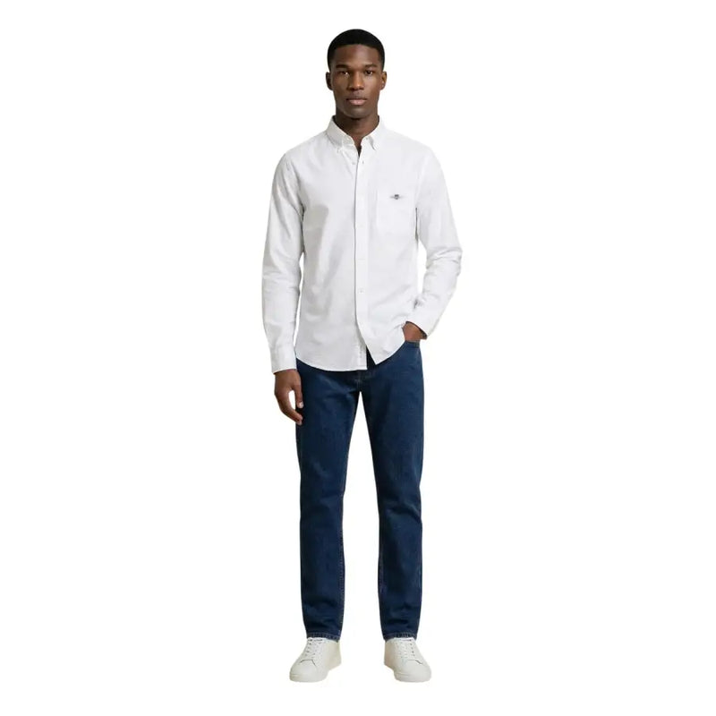 Chemise blanche à manches longues Gant pour homme, avec logo brodé discret sur la poitrine gauche, confectionnée dans un tissu de haute qualité.