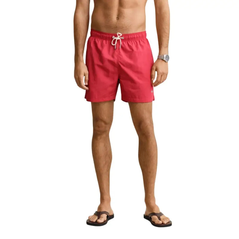 Short de bain homme Gant en polyamide bleu clair, présenté ici avec un slip de bain rouge à ceinture blanche à cordon.