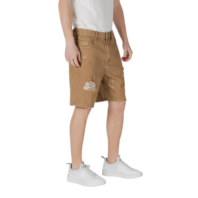 Brown denim cargo shorts with distressed patches and white sneakers