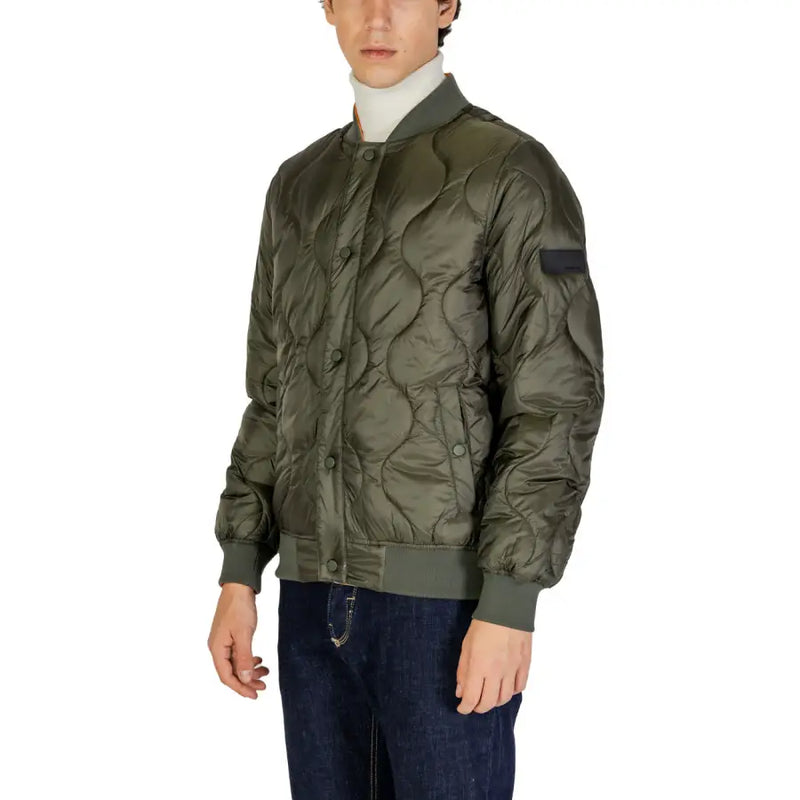 Olive green quilted bomber jacket with black panel on sleeve and white turtleneck sweater underneath.