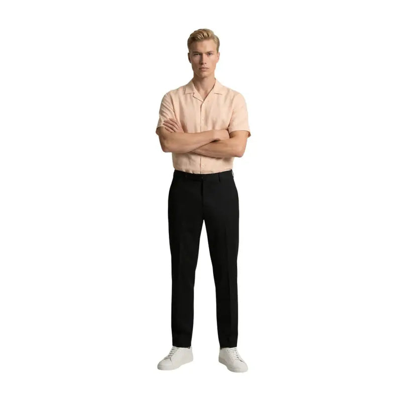 Un homme portant gianni lupo Pantalon noir en polyester viscose pour homme, porté avec une chemise à manches courtes pêche clair et des baskets blanches.
