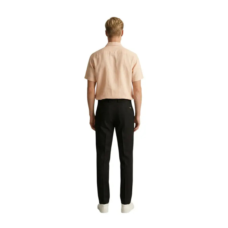 Un homme portant Gianni Lupo Pantalon noir en polyester viscose pour homme, porté avec une chemise à manches courtes pêche clair