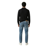 Un jean en denim bleu moyen avec un écusson de marque en cuir marron sur la ceinture arrière. gianni lupo