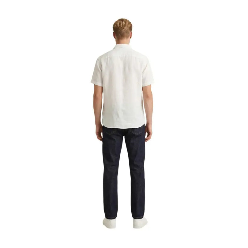 Un homme portant un Gianni Lupo Chemise homme blanche à manches courtes en coton, portée avec un jean bleu foncé