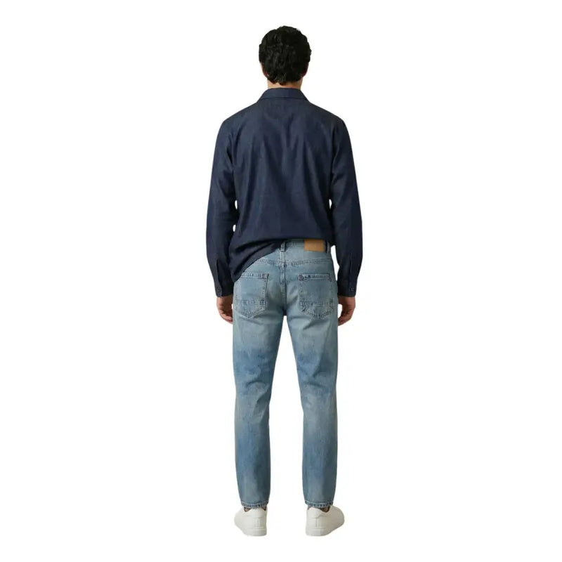 Un jean en denim clair délavé, coupe classique cinq poches et délavage subtil pour homme, par gianni lupo
