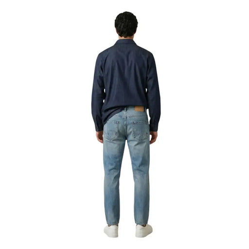 Un jean en denim clair délavé, coupe classique cinq poches et délavage subtil pour homme, par gianni lupo