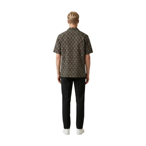 Un homme portant un gianni lupo Chemise homme marron foncé à manches courtes, ornée d'un motif géométrique doré complexe.