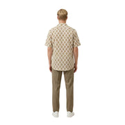 Un homme portant un beige Gianni Lupo Chemise pour homme à manches courtes, ornée d'un motif géométrique répété marron et crème.