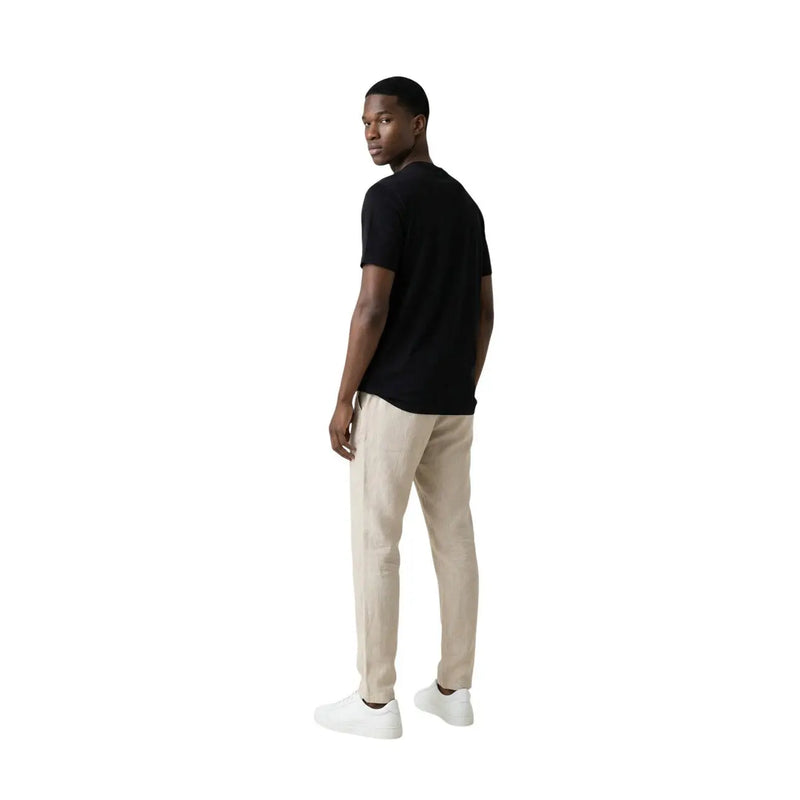 A man wearing a black short-sleeved Gianni Lupo men t-shirt paired with beige trousers in a casual style