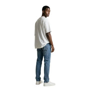 Un homme portant un gianni lupo T-shirt blanc à col rond 100% coton, porté avec un jean bleu délavé.