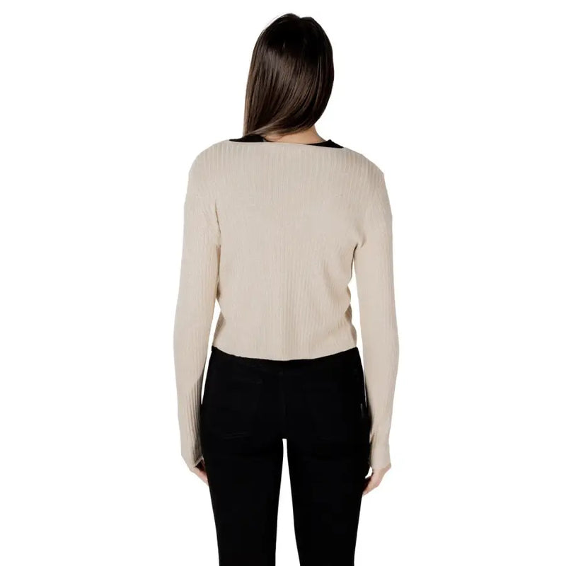 Beige ribbed knit long sleeve top with black trim at neckline shown with gold lurex button front cardigan with v neck
