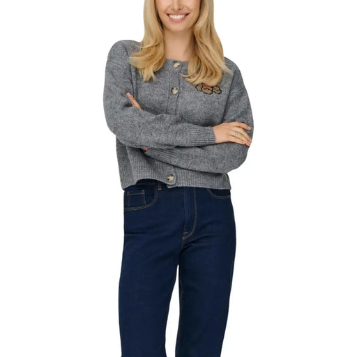 Women wearing a gray printed long button-front round neck cardigan with dark blue jeans