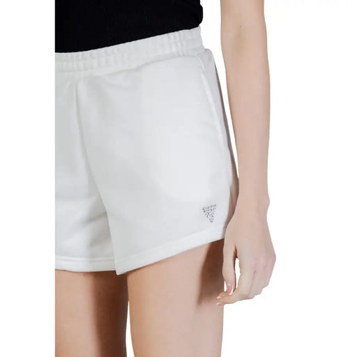 Guess Active Short de sport blanc en coton et polyester pour femme, avec taille élastique et logo brodé sur le bas de la jambe droite.
