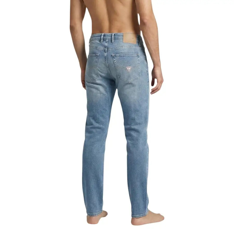 Denim délavé Guess Jean homme en coton stretch bleu, coupe classique cinq poches et logo sur la poche arrière
