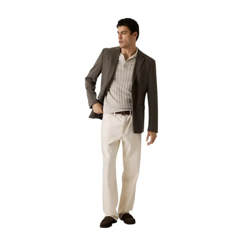 Un homme portant un Guess Polo beige à manches courtes en coton viscose pour homme, porté avec un blazer gris foncé et un pantalon crème.