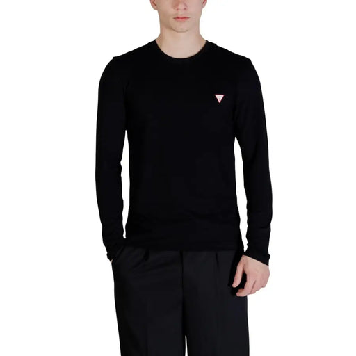 Guess Pull noir à manches longues et col rond pour homme, en coton, avec logo triangulaire rose sur la poitrine gauche.