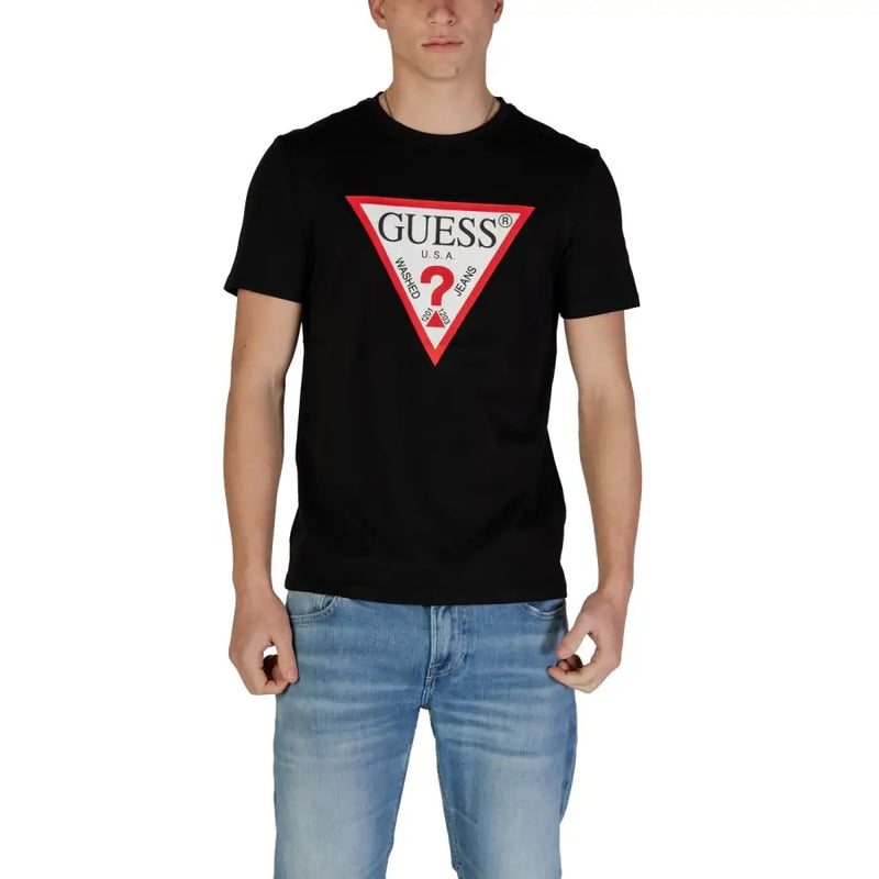 Noir Guess hommes t-shirt avec un logo triangulaire rouge et blanc audacieux, le nom de la marque et le texte « jeans délavés ».