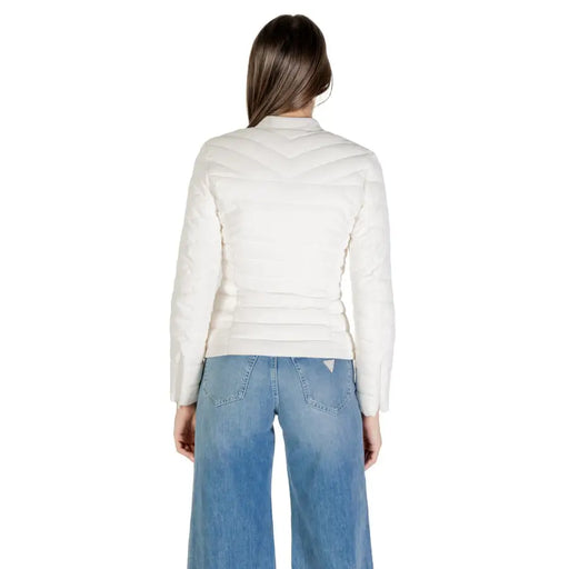 Woman wearing a white puffer jacket and blue wide-leg jeans, showcasing Guess Women Beige Long Zip Front Jacket