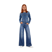 A woman wears a Guess women blue cotton blazer Ivy jacket with two chest pockets and matching medium-wash denim jeans