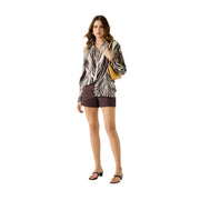 A woman wears a black and white zebra print blouse paired with Guess women brown viscose long classic round neck shirt
