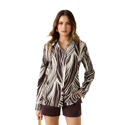 A woman wears a Guess women brown viscose long classic round neck shirt with bold black and white leaf patterns