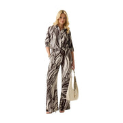Une femme porte une combinaison pantalon en viscose à imprimé zèbre noir et blanc, à manches trois-quarts et jambes larges.