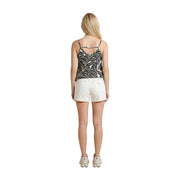 A woman wears Guess women white cotton shorts super relaxed fit paired with a black and white patterned spaghetti strap top