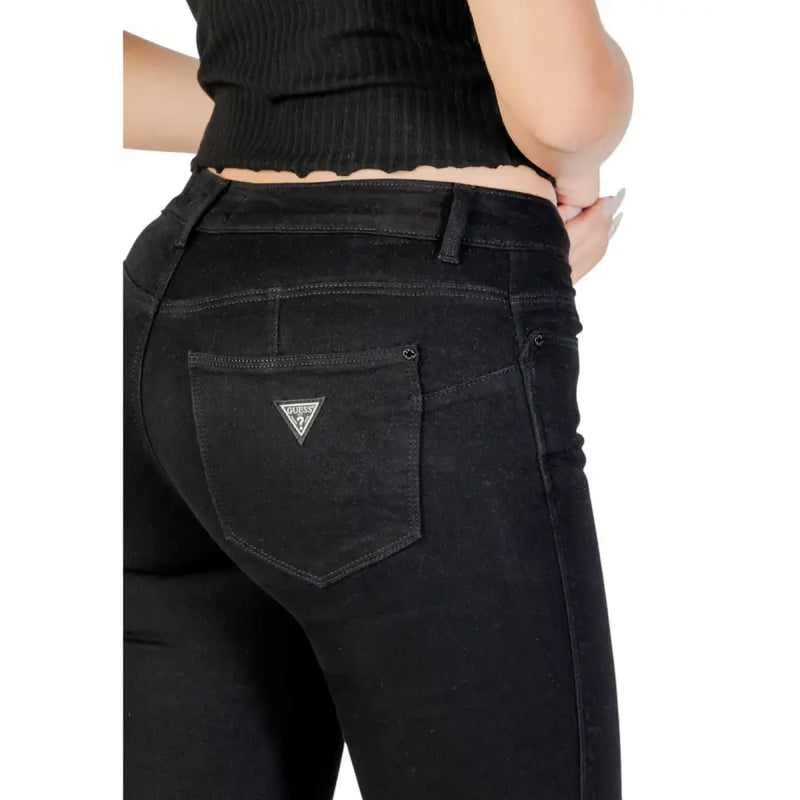 verso de guess Jean noir pour femme avec poches, légèrement usé et orné d'un logo triangulaire brodé.