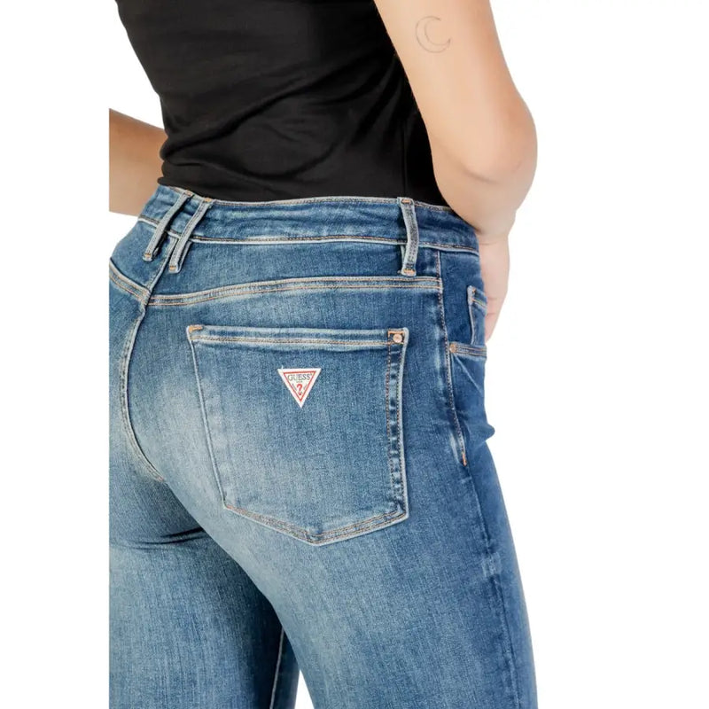 verso de guess Jean en denim bleu pour femme, effet usé, avec un écusson logo triangulaire rouge et blanc sur la poche