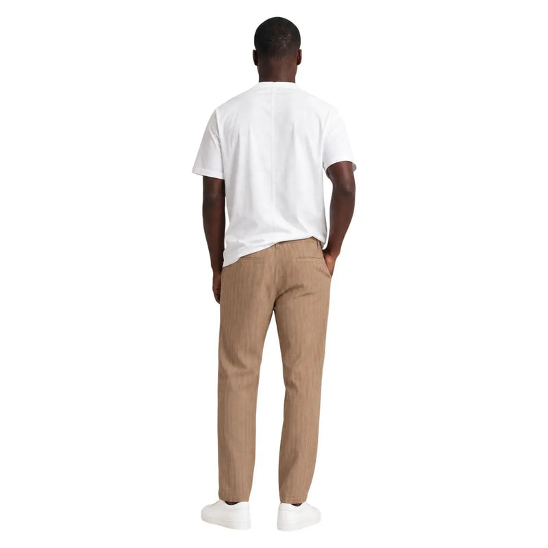 Pantalon chino beige à fines rayures et coupe classique, porté avec un t-shirt blanc en coton Hydra pour homme à col rond.