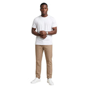 Un homme portant un t-shirt blanc à col rond en coton Hydra Men, un pantalon beige à fines rayures et des baskets blanches.