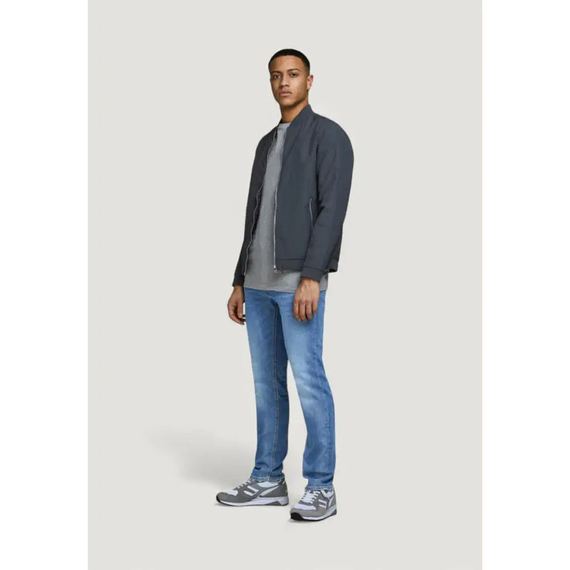 Blouson aviateur gris foncé au design moderne et épuré, orné d'une fermeture éclair discrète sur le devant, porté avec un jean bleu Jack & Jones à l'effet usé.