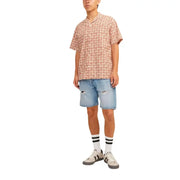 Un homme portant une chemise à manches courtes à motif de crâne, associée à un short en coton bleu clair Jack & Jones pour hommes