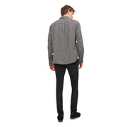 Un homme portant une chemise à carreaux noirs et blancs à manches longues et col boutonné, ainsi qu'un jean noir Jack & Jones pour homme