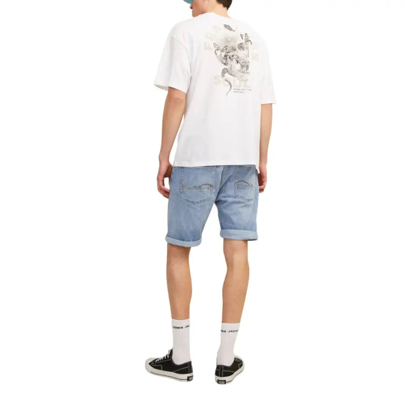Back view of a white t-shirt with a detailed black and gray skull graphic paired with jack & jones men’s blue shorts