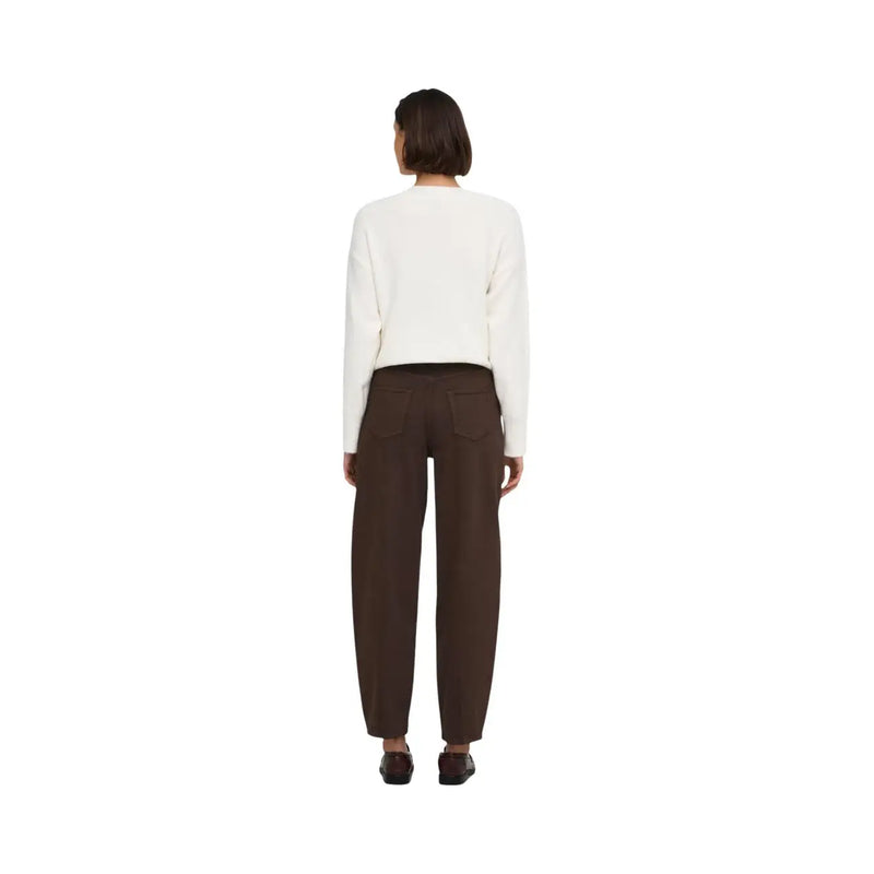 Une femme porte un jean Jacqueline De Yong marron en coton, associé à un pull crème. top