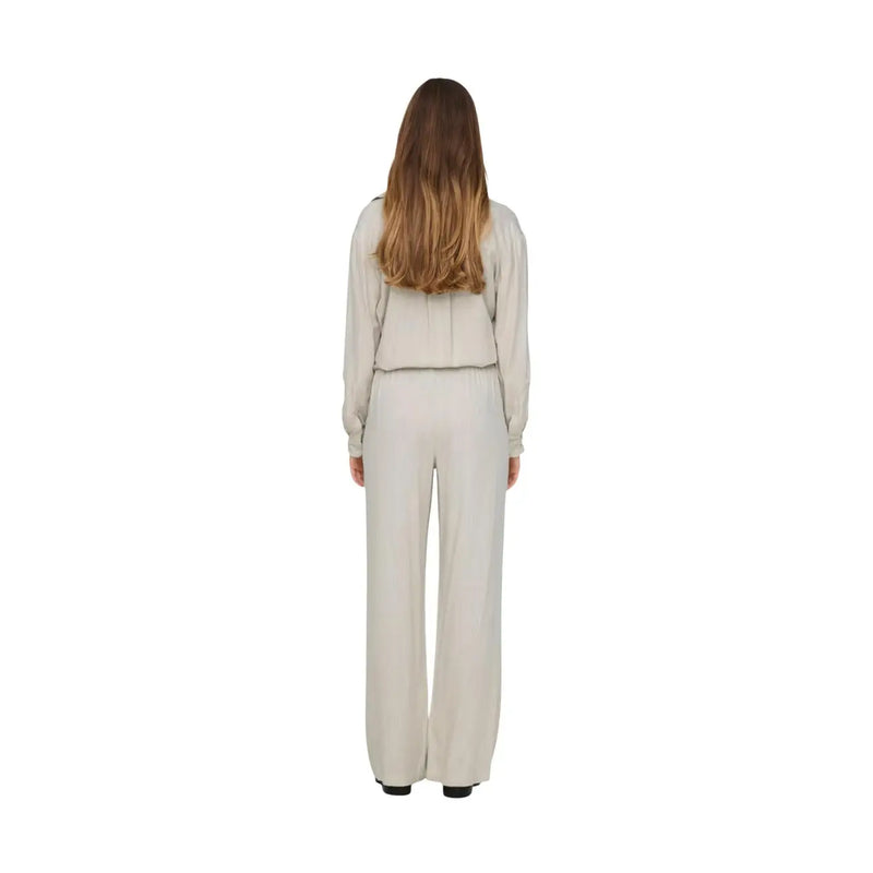 Une femme portant un pantalon en lin gris Jacqueline de Yong, coupe classique, vue de dos avec un haut blanc cassé top